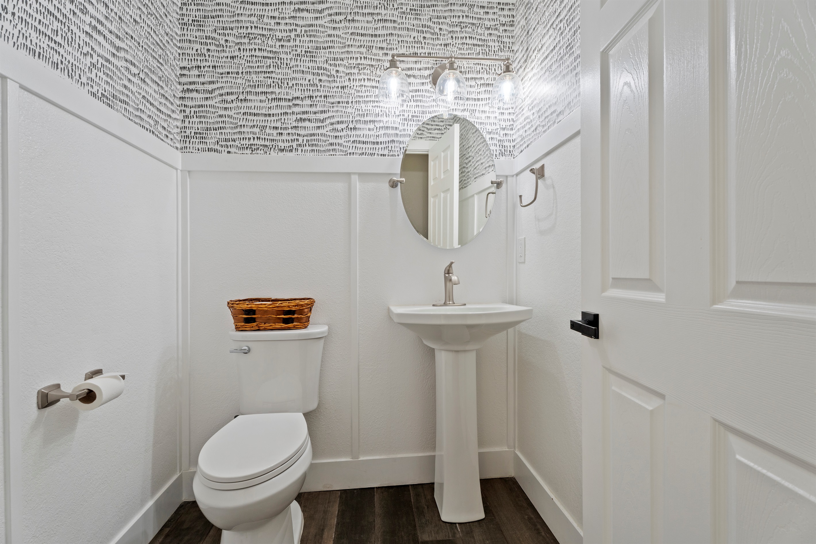 Modern and artistic, this half bath features sleek fixtures, eye-catching wallpaper, and a clean, polished design.