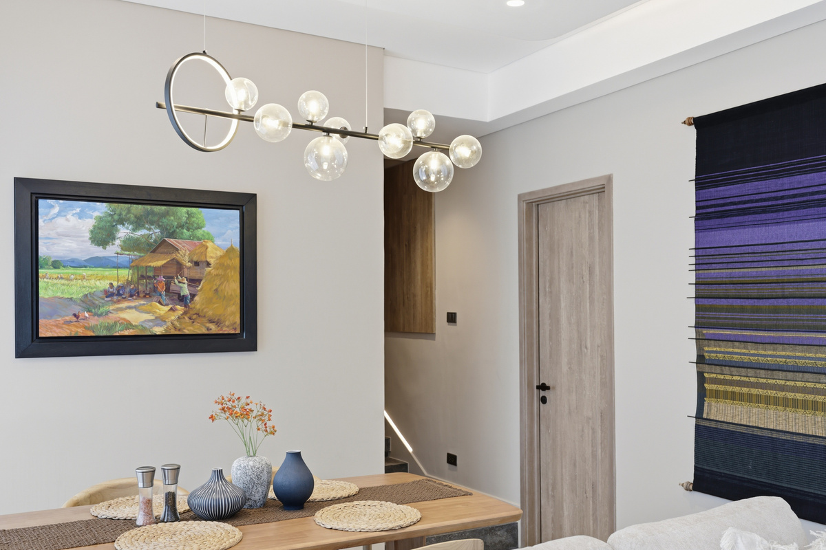 Bedroom with wood dining table, framed landscape art, pendant lighting, and modern decor in neutral tones.