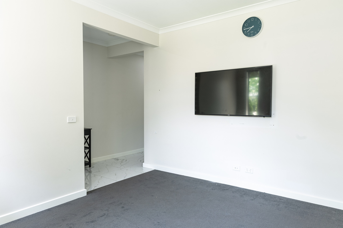 Second living area with wall-mounted TV and carpeted flooring.