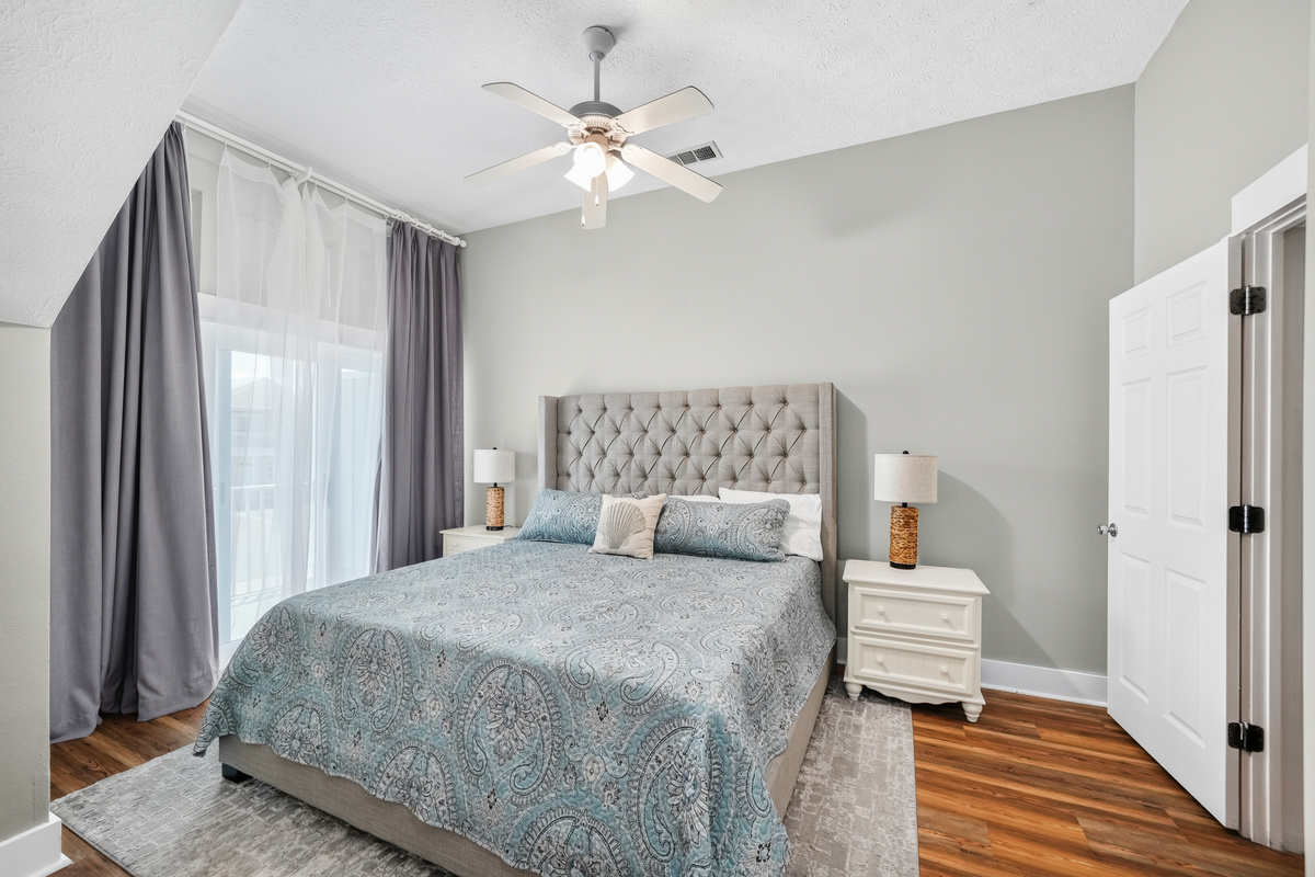 Bedroom 2: King-size bed, premium linens, ceiling fan, dresser, bedside lamp, spacious closet, and a bright private balcony, perfect for a relaxing stay.