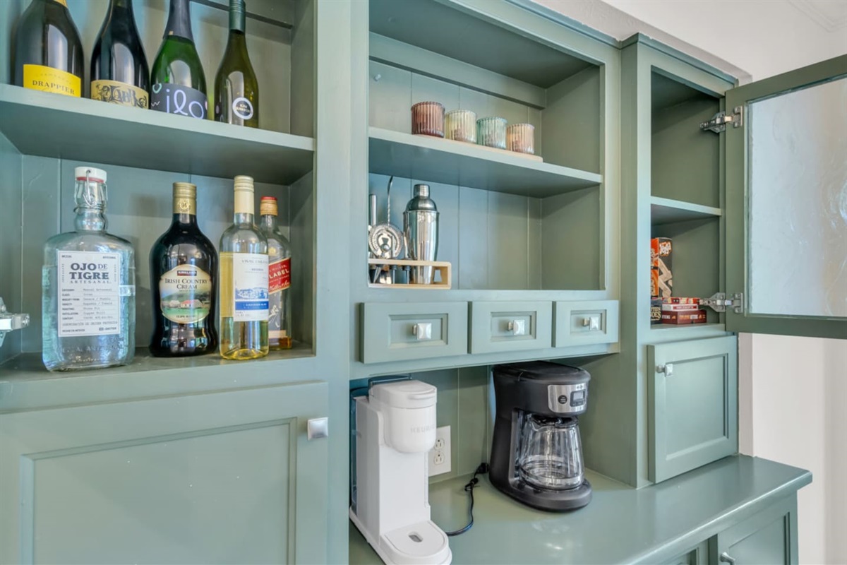 Stylish bar area equipped with a cocktail shaker, drip coffee machine, and Keurig coffee maker for both morning brews and evening drinks.