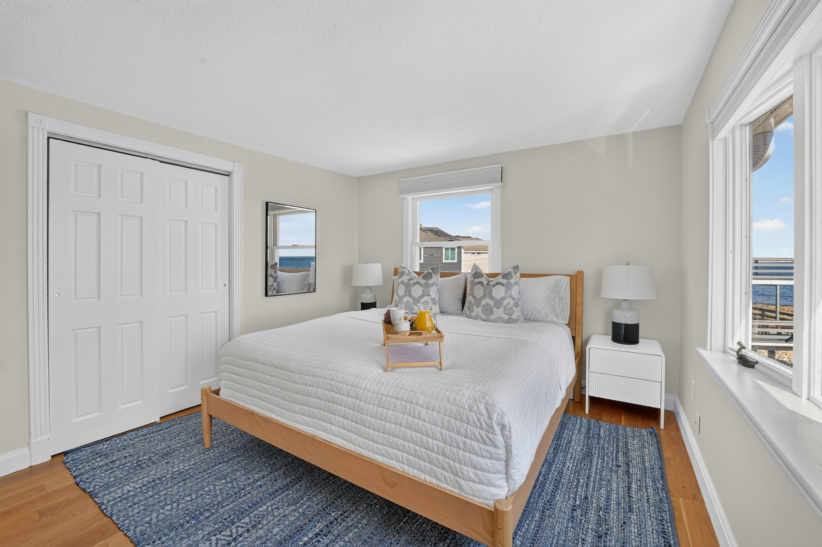 Bright bedroom with a comfortable bed, generous natural light, and a calm coastal atmosphere.
