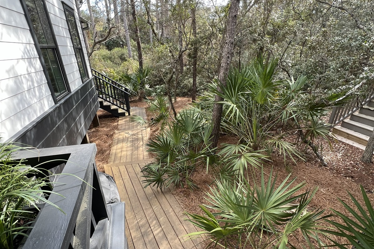 Boardwalk along the side of the home from the front entrance. Leads to the screened-in porch stairs and a private backyard with seating.