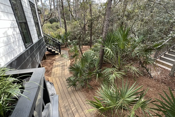 Boardwalk along the side of the home from the front entrance. Leads to the screened-in porch stairs and a private backyard with seating.