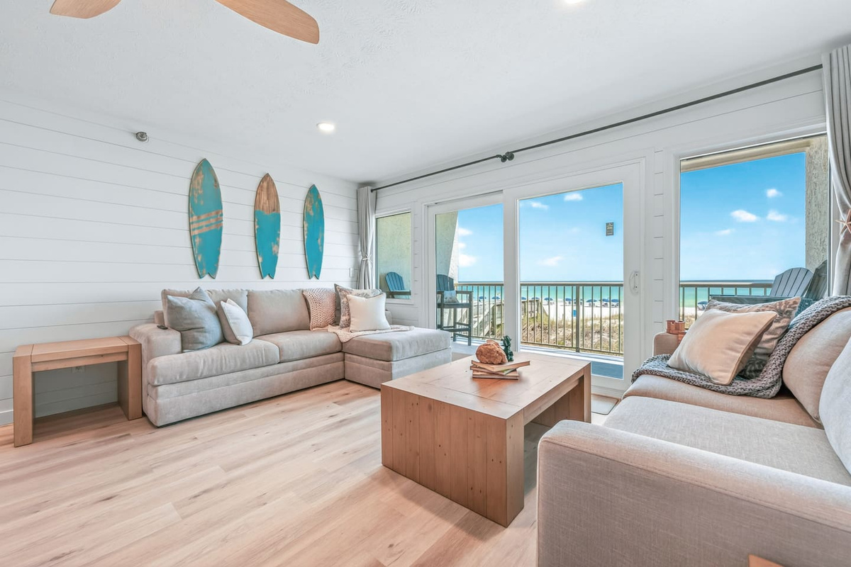 Bright, fully renovated living room with hardwood floors, shiplap walls, and floor-to-ceiling Gulf views — where the Emerald Coast becomes your backdrop at El Secreto Azul, Destin Beach.