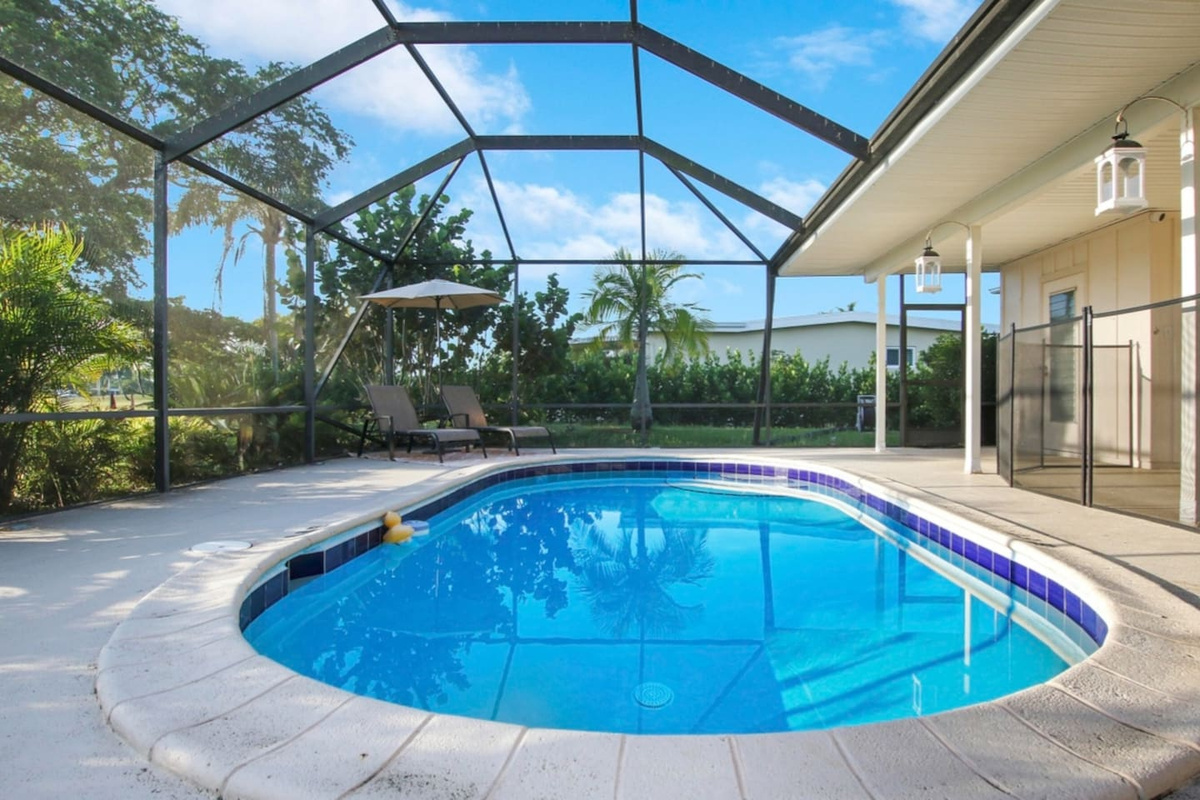 Screened in pool area with lounge chairs. This pool area is perfect for all times of year. During the day you can get a view of the golf course while getting a tan or taking a swim. There is also more seating in the covered area. 
