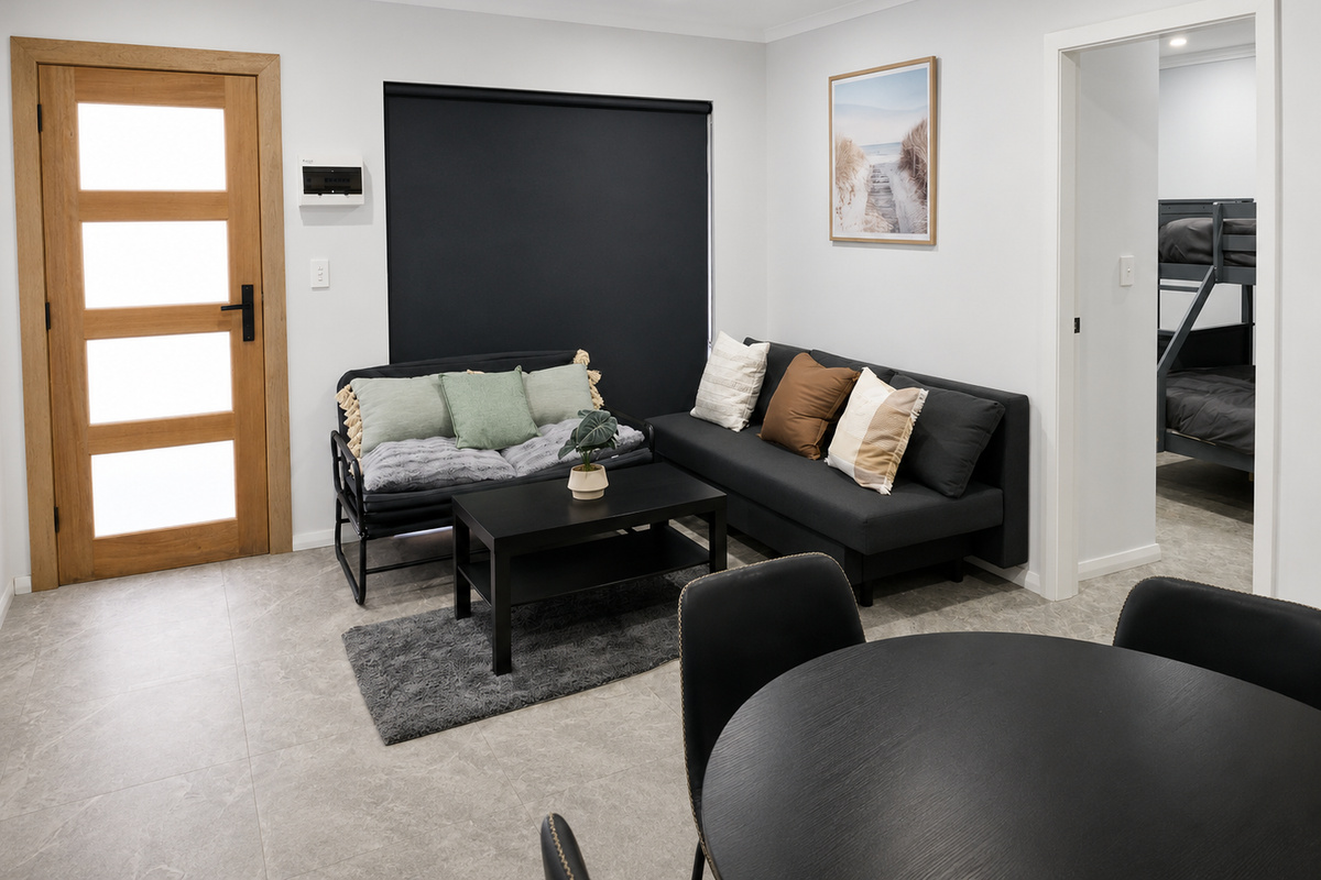 The timber door, black accents and neutral lounge styling create a strong contrast throughout the living area.