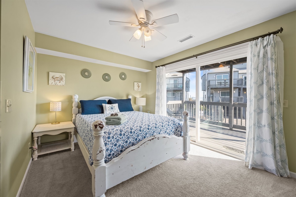 Comfortable queen bedroom with coastal colors and sliding doors that lead straight to the balcony for fresh ocean air