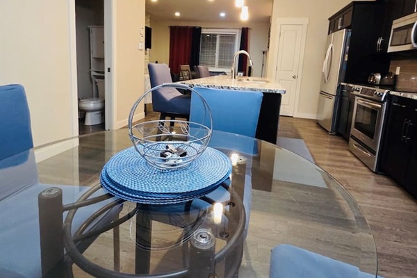 Sleek open kitchen with island seating, stainless appliances, chic dining.