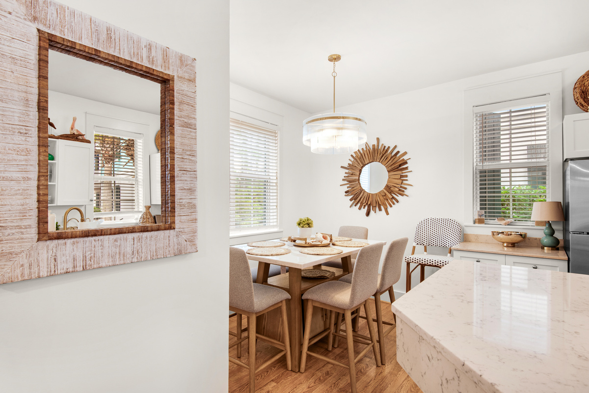 Seagrove Bungalow 103 dining table beside the kitchen, with upholstered chairs and window light.