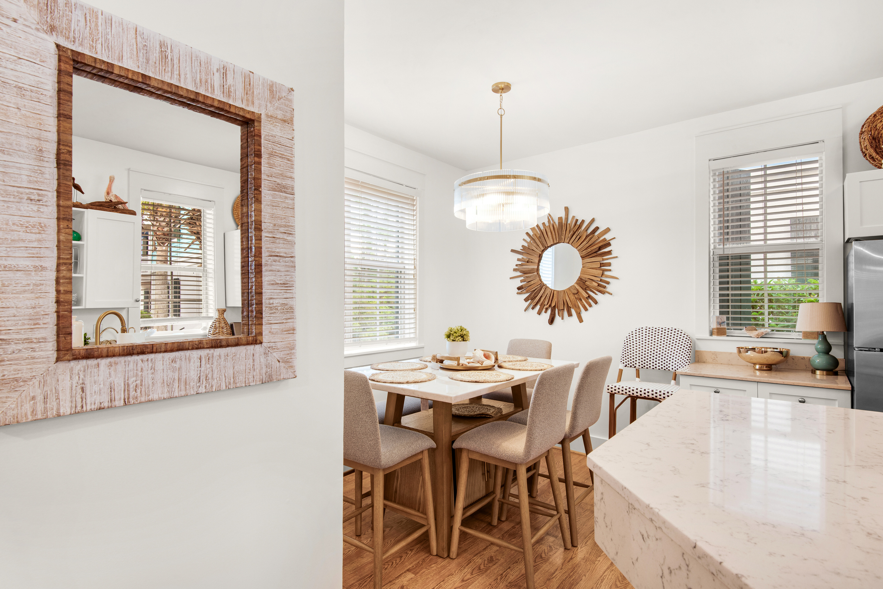 Seagrove Bungalow 103 dining table beside the kitchen, with upholstered chairs and window light.