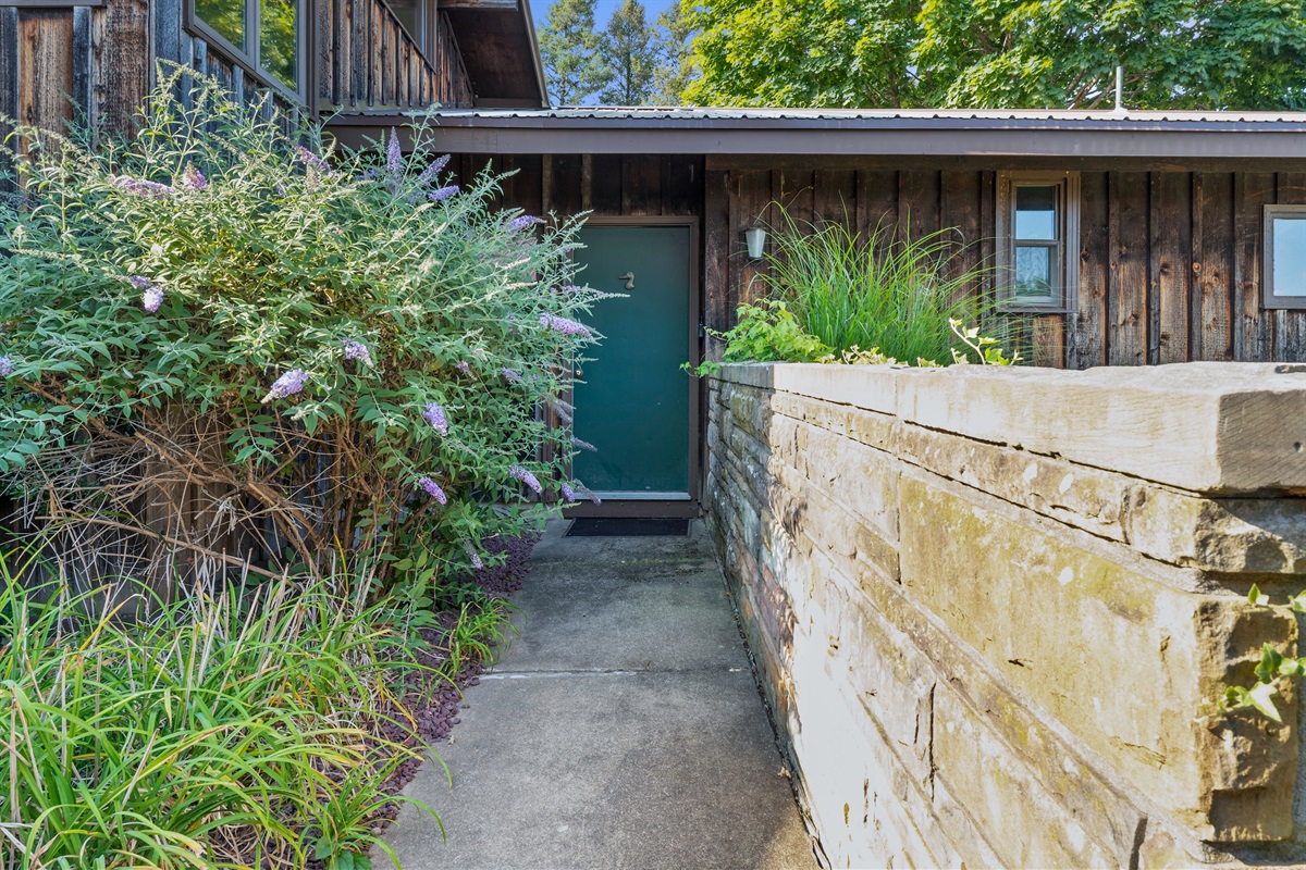 Rustic entry with bold green door and large windows welcoming natural light into the home.