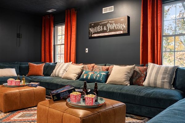 Movie night paradise: a huge sectional, cozy lighting, and space for everyone to pile in