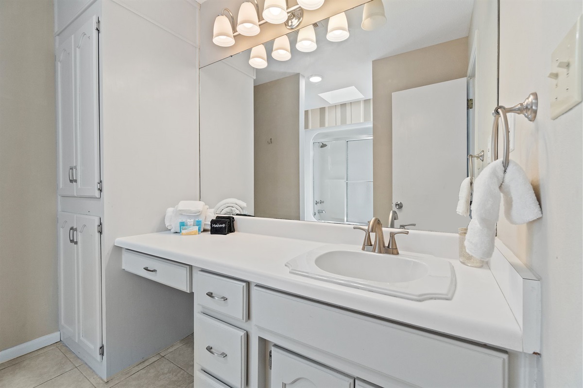 This spacious bathroom features a large mirror, soft lighting, and a long vanity with plenty of drawers for your essentials. Fresh towels and toiletries are provided to make your stay easy and comfortable.
