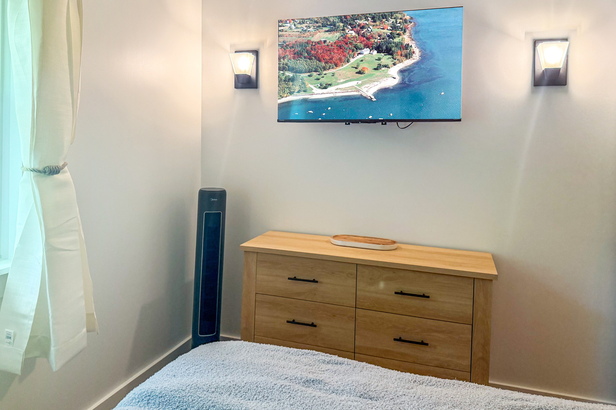 Relax in front of the large wall-mounted flat-screen TV in the king room. Positioned over a matching light-wood dresser, the media center is accented by twin modern wall sconces, with a sleek oscillating tower fan provided for your comfort.