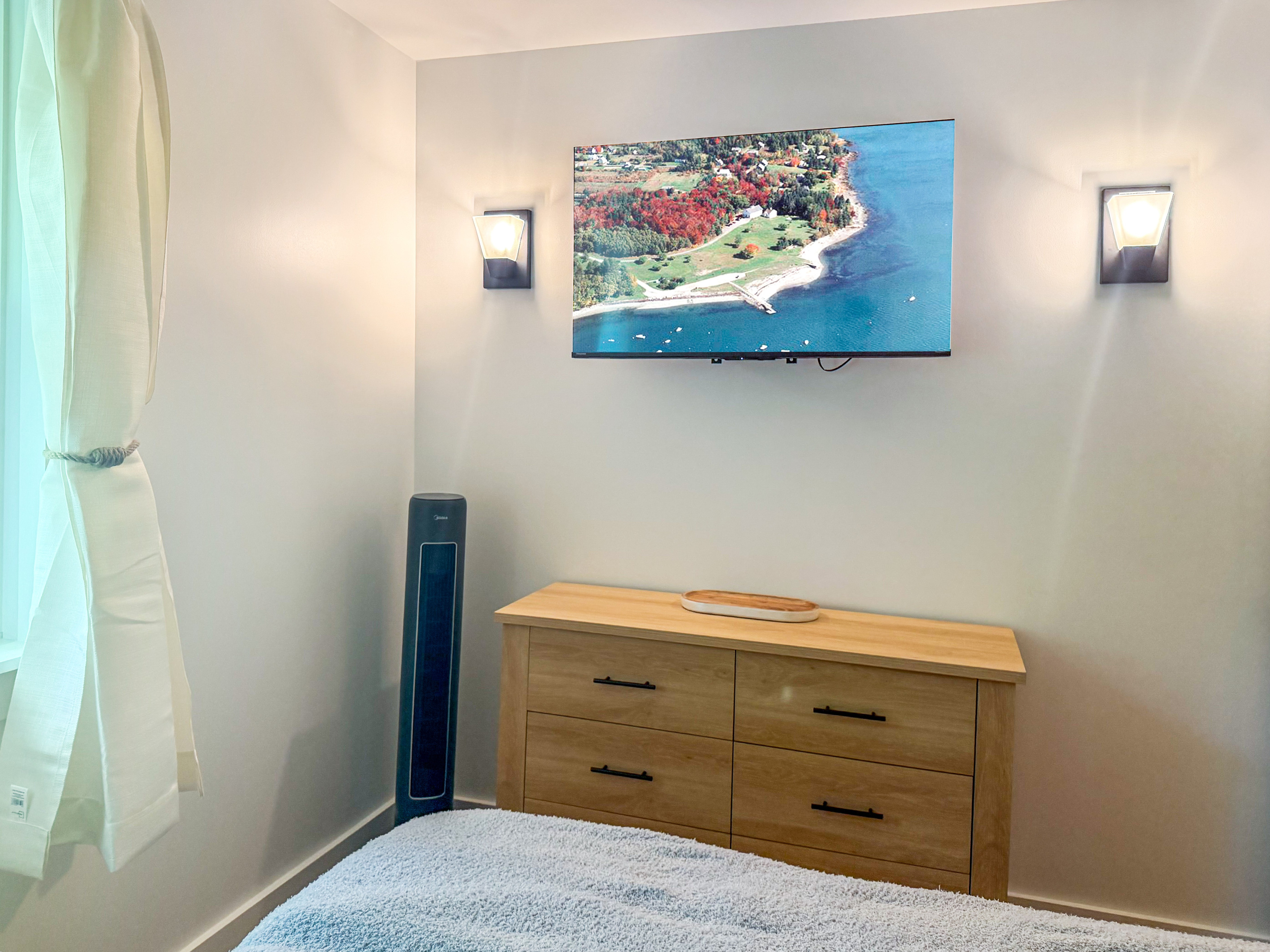 Relax in front of the large wall-mounted flat-screen TV in the king room. Positioned over a matching light-wood dresser, the media center is accented by twin modern wall sconces, with a sleek oscillating tower fan provided for your comfort.