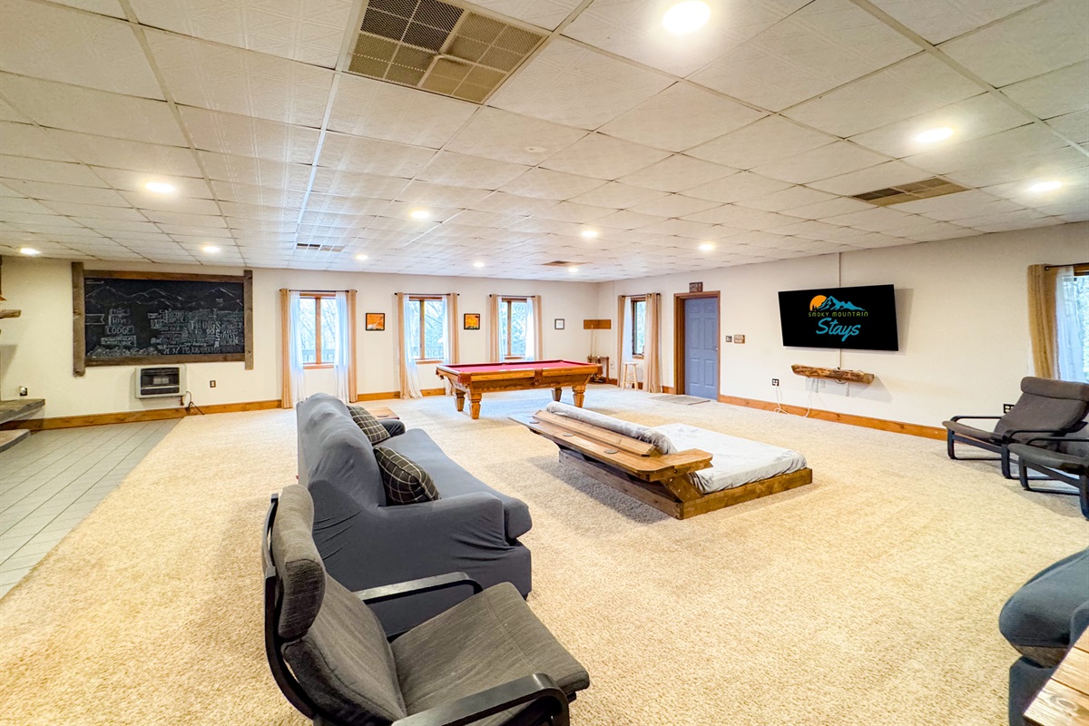 lower level living room complete with a 70" Smart TV, plenty of seating, bar area, and pool table