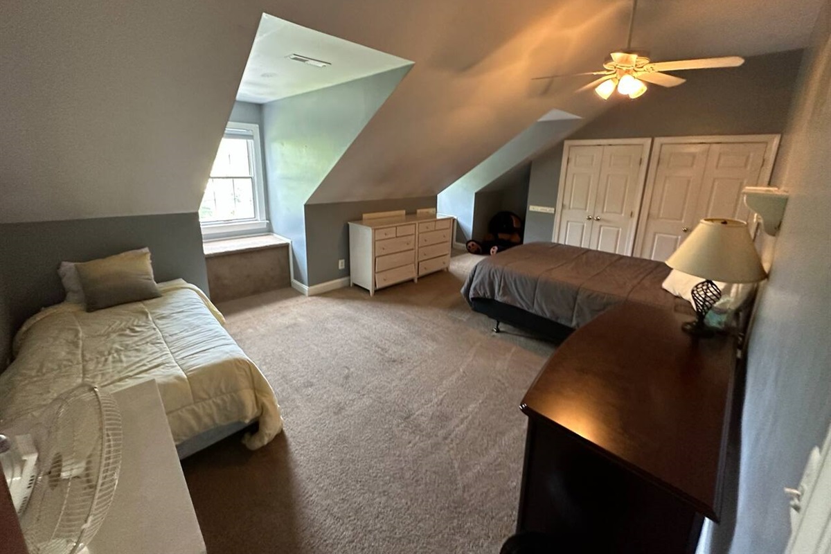 Bedroom 3 (BR3) with 1 Queen bed and one Twin bed. Has 2 dormers, 2 Closets, a Dresser, and a storage table.