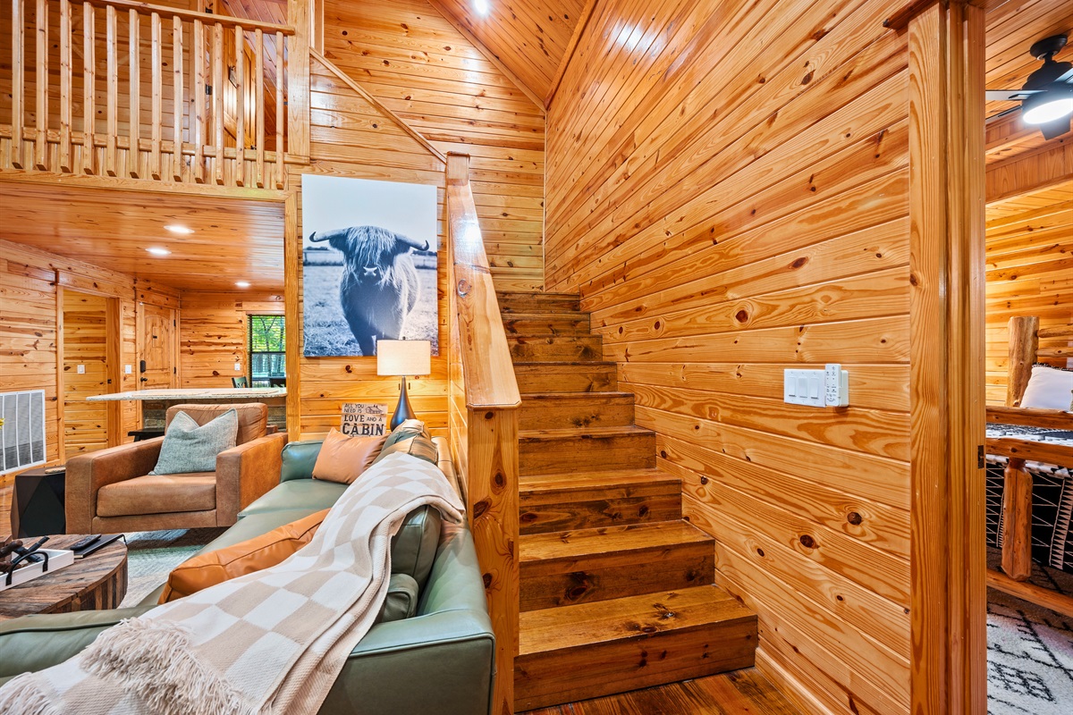 Stairway from the loft overlooking the lower level, with cozy throws and welcoming design touches.