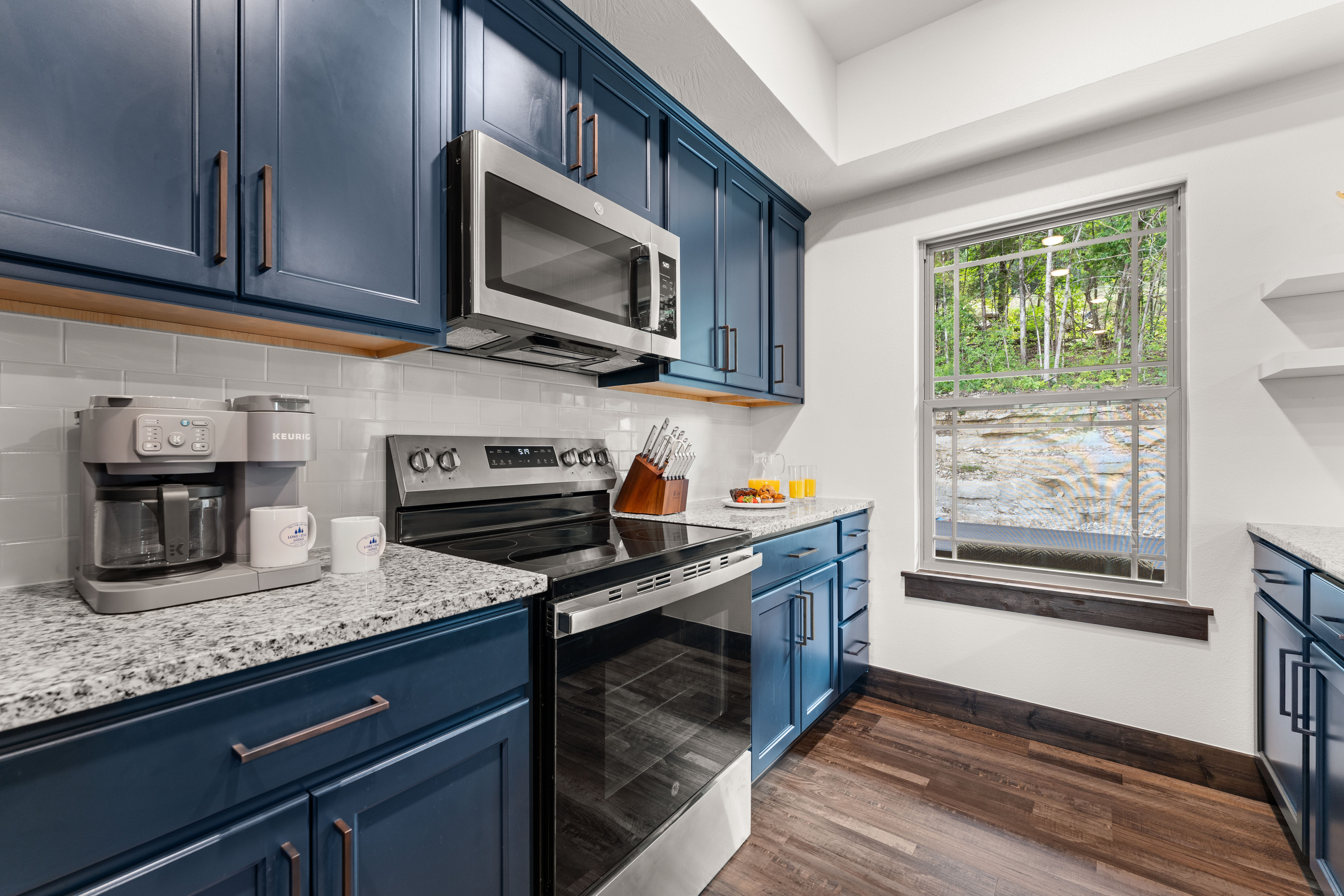 The fully equipped navy kitchen has granite counters, stainless appliances, a coffee bar, and a creekside window.