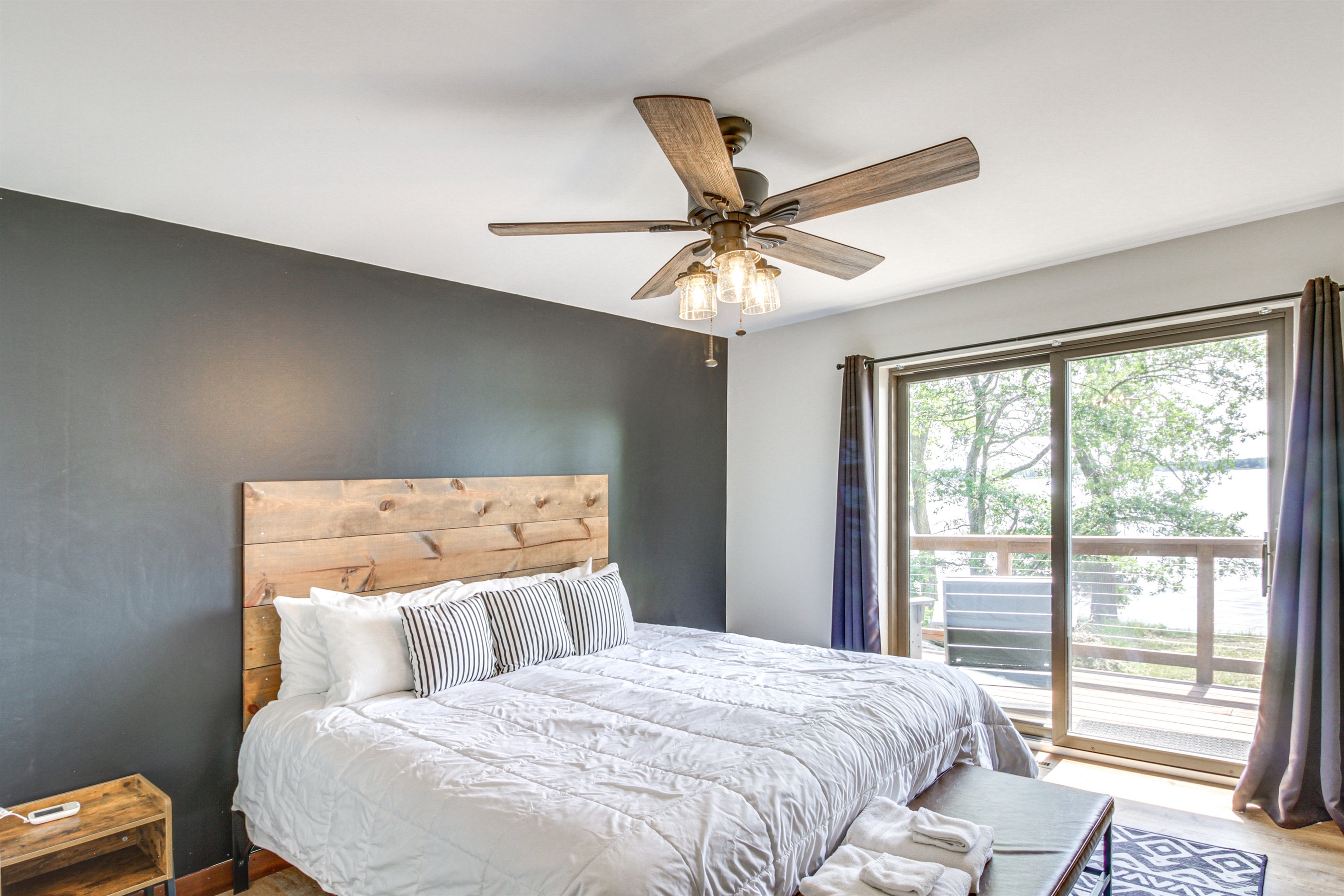 Primary bedroom with king bed, ceiling fan, and sliding doors to the deck with lake views
