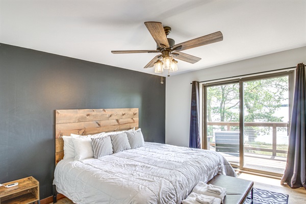 Primary bedroom with king bed, ceiling fan, and sliding doors to the deck with lake views