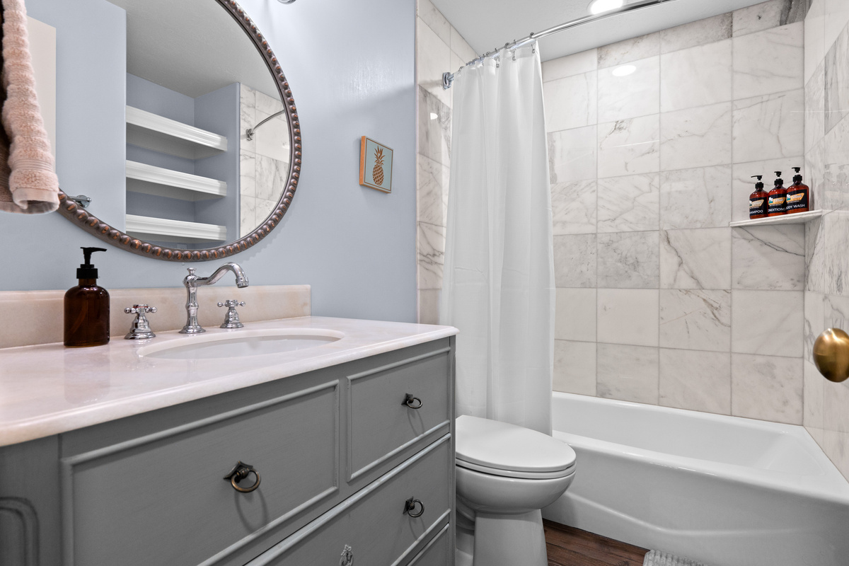 This beautifully finished bathroom pairs a vanity with polished fixtures, tile surrounds, and a full tub-shower combination.