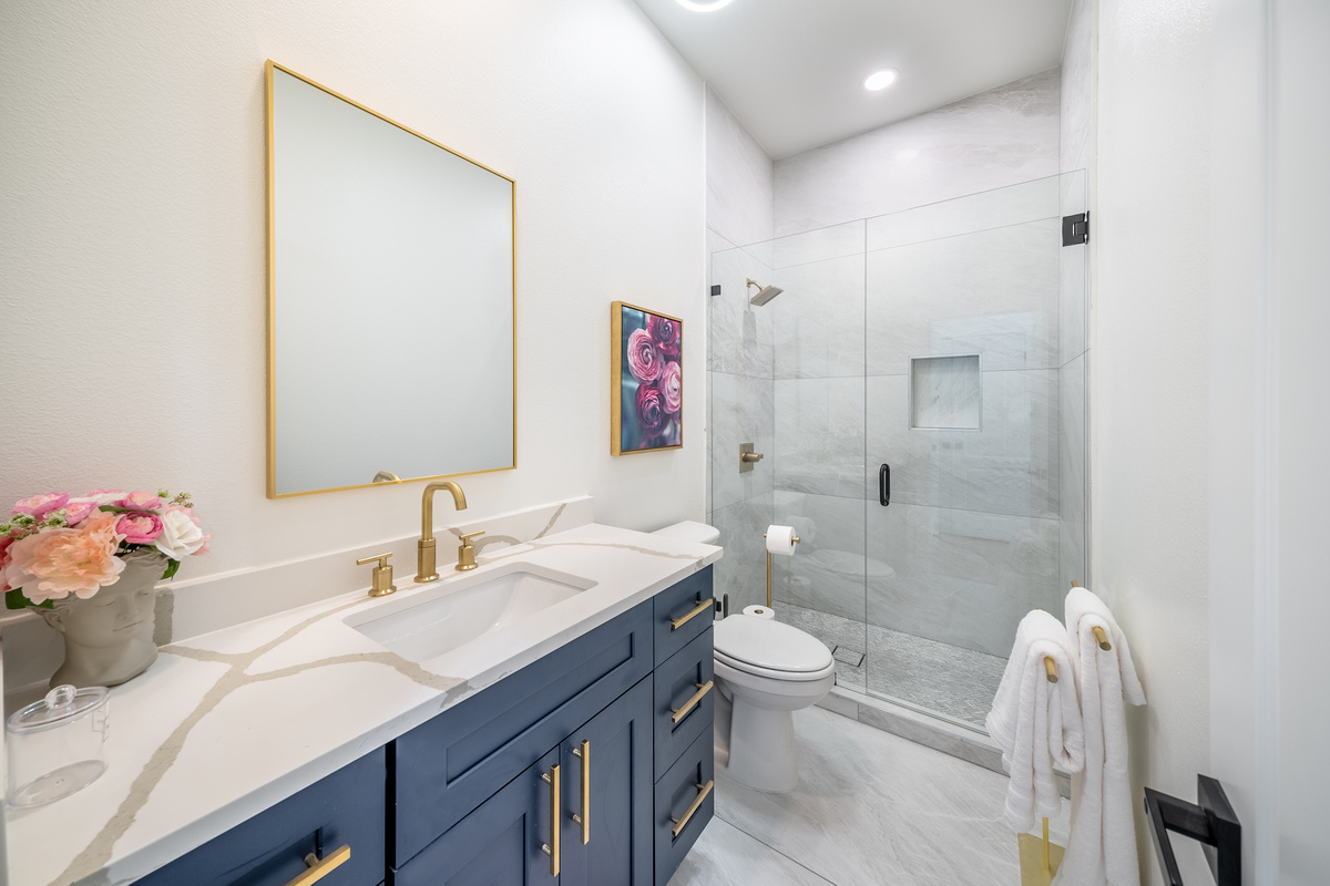Spa-style bathroom featuring a glass walk-in shower and gold accents.