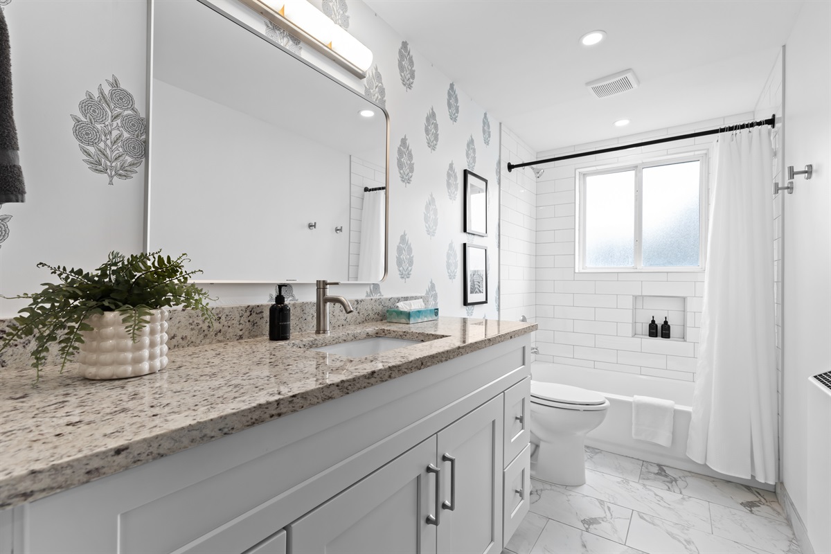Fresh, modern bathroom featuring granite vanity, full-size tub/shower combo, and bright natural light.