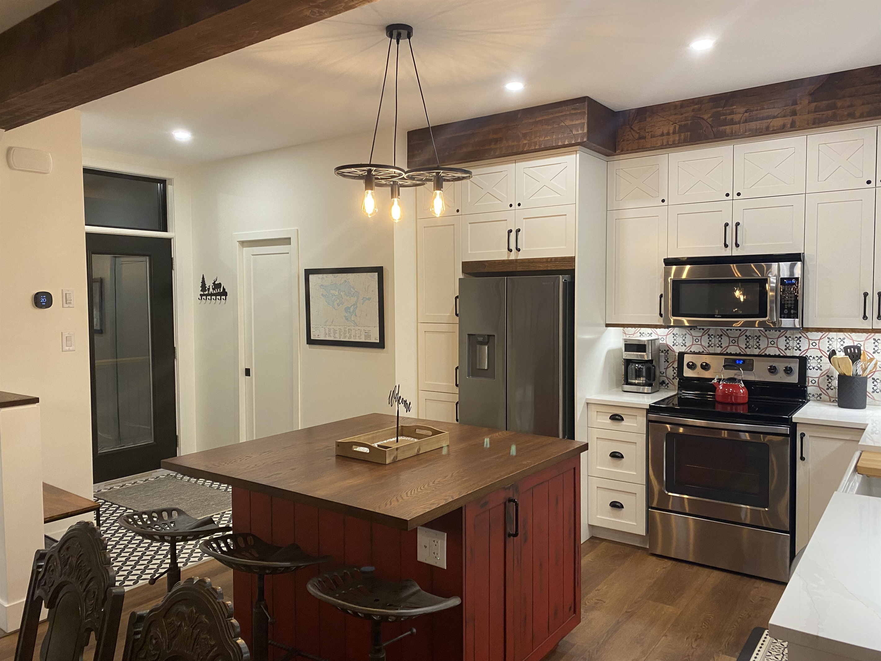 Well-equipped kitchen with island, custom cabinetry and cottage main entrance door  nearby