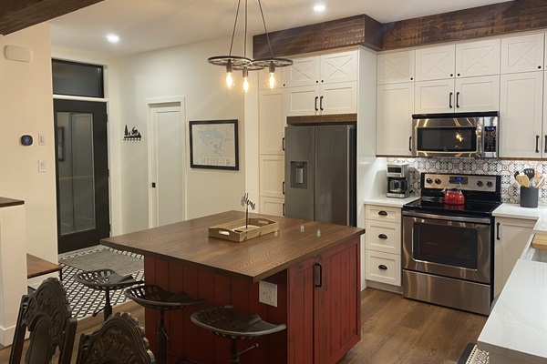 Well-equipped kitchen with island, custom cabinetry and cottage main entrance door  nearby