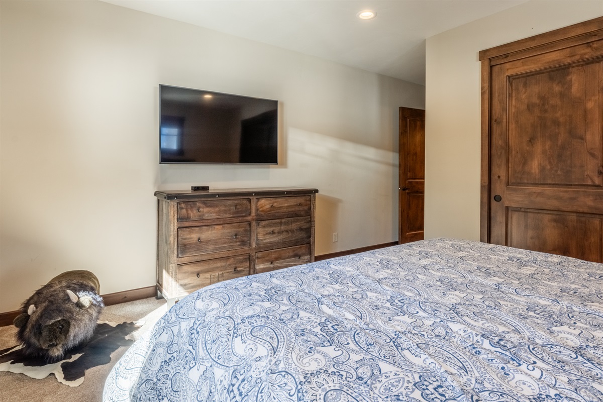 This en-suite is complete with a rustic hide rug underfoot, a bear statue standing guard, and a Smart TV for unwinding after a day on the slopes. 