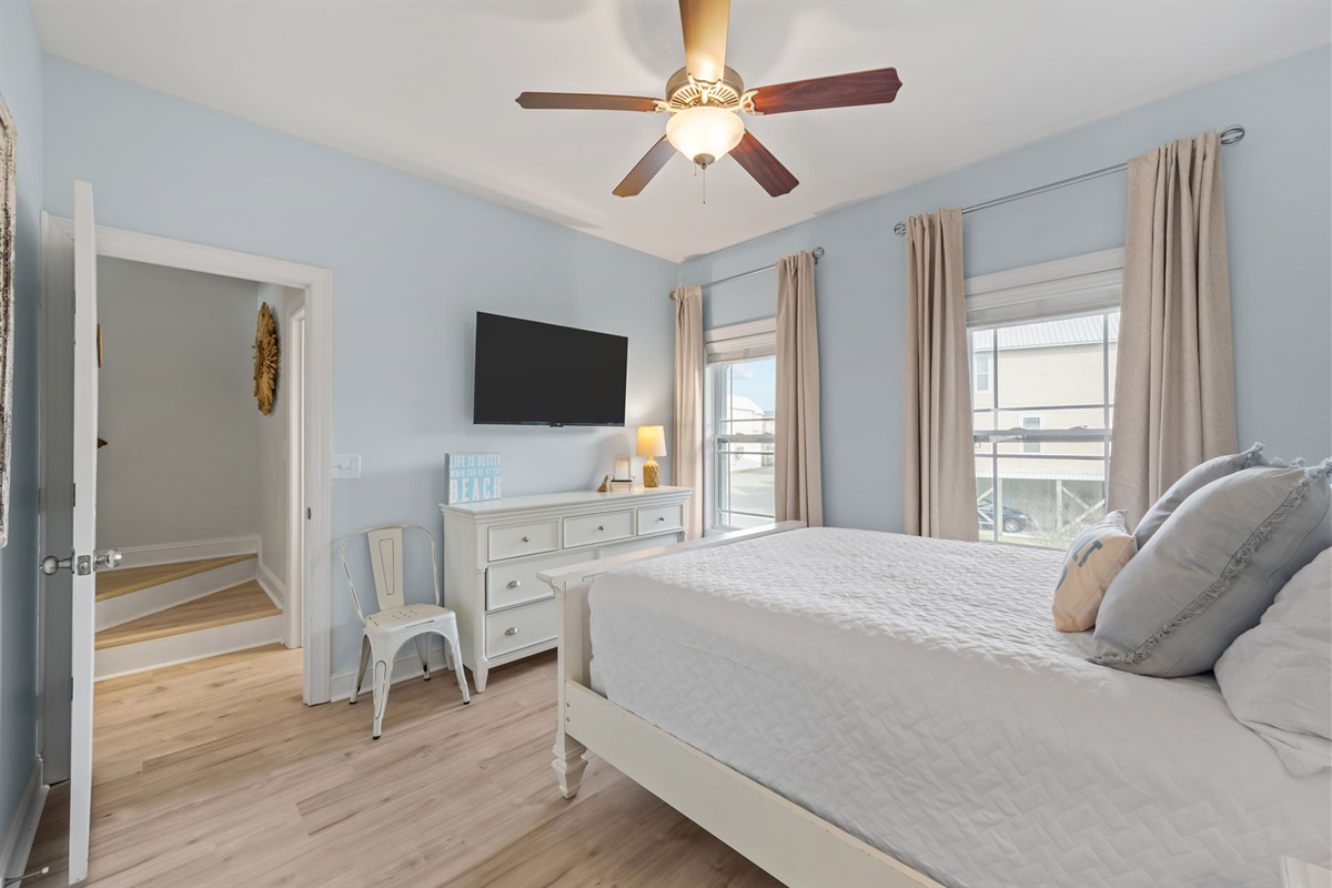 3rd bedroom on the 1st floor with a cozy queen bed, crisp white linens, natural light flooding in, and smart TV