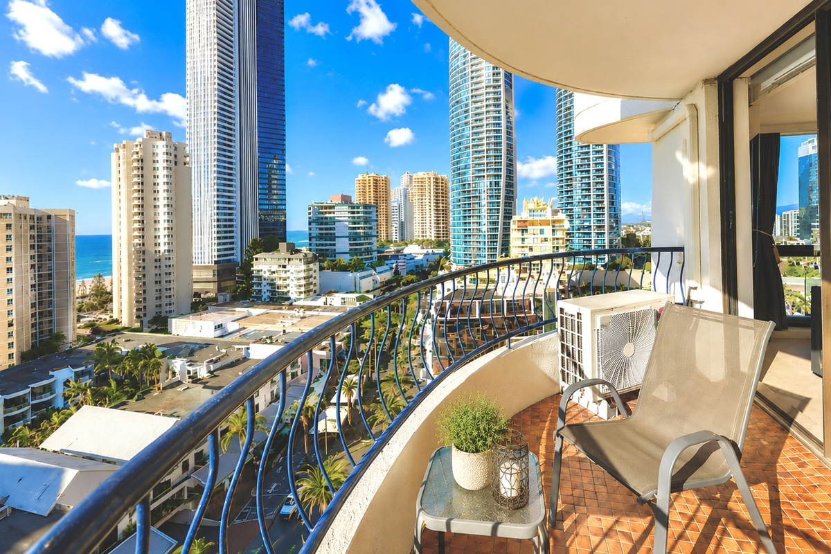 Curved balcony rails frame ocean, skyline and city views, giving the apartment a memorable open-air vantage point above Surfers Paradise.