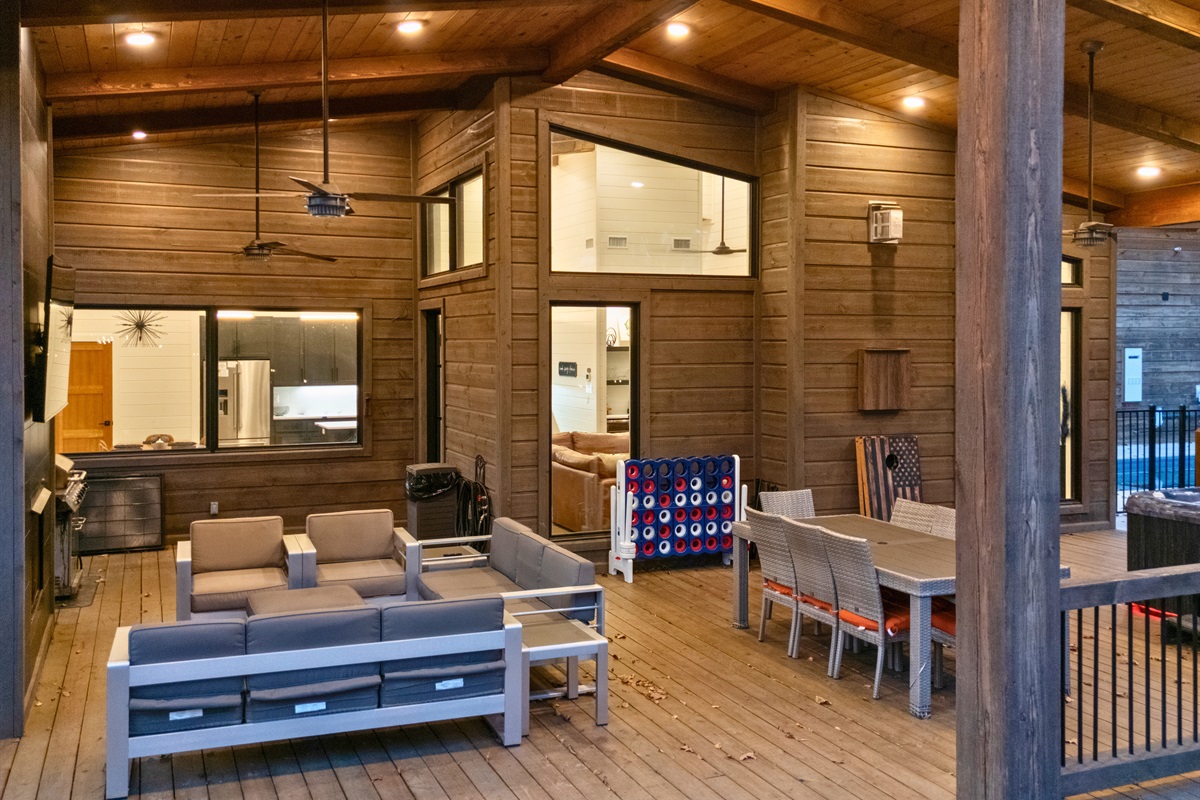 The covered outdoor living area offers tons of space to gather with comfy seating, a big dining table, ceiling fans, and games that make hanging out here an all-day thing.