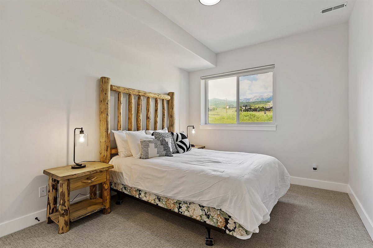 A serene and elegantly appointed bedroom with a luxurious queen bed, soft textures, and abundant natural light for a restful retreat.