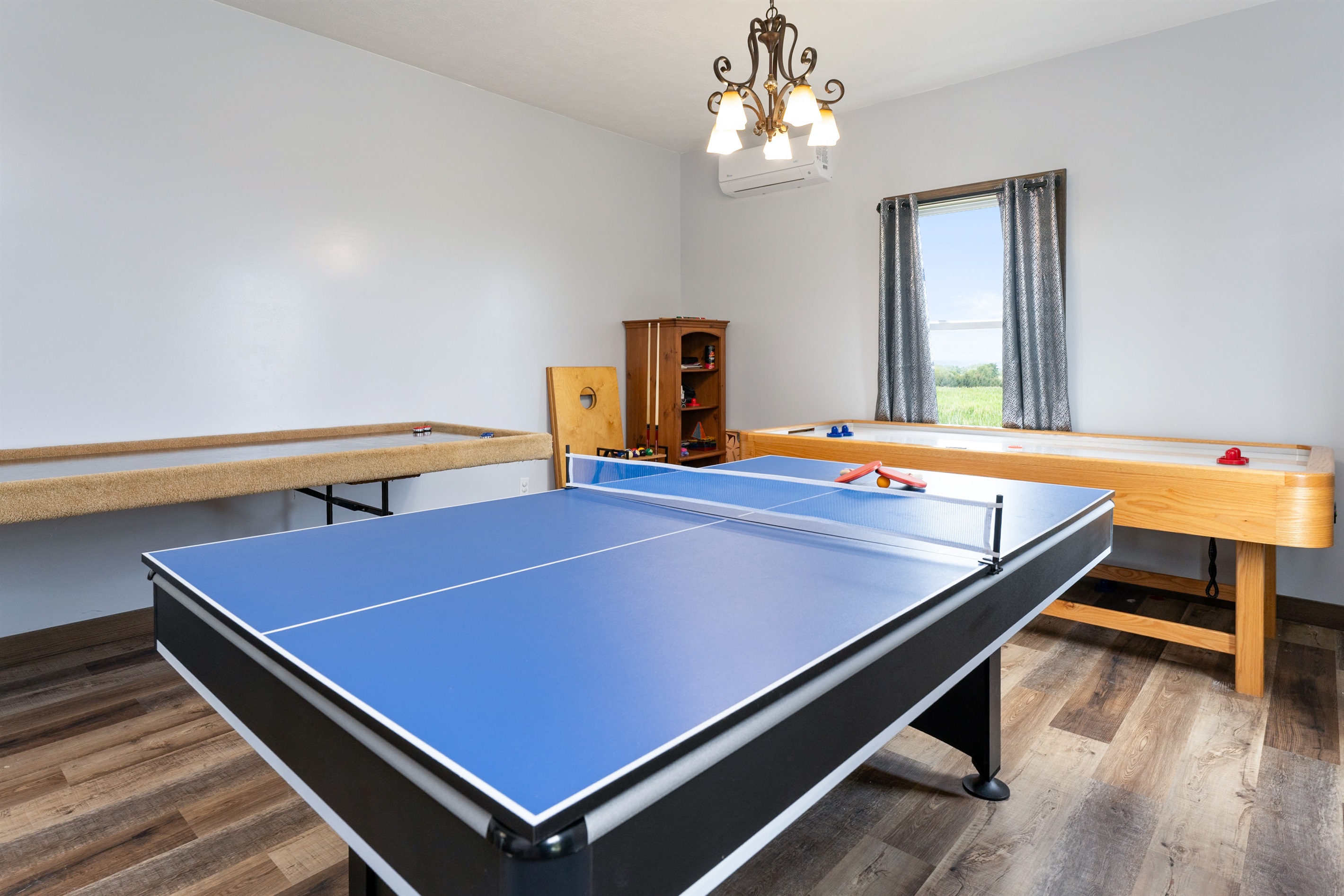 Entertainment-ready game room featuring a combination ping pong/pool table, shuffleboard, and air hockey with several board games and Cornhole for outside..... endless fun!