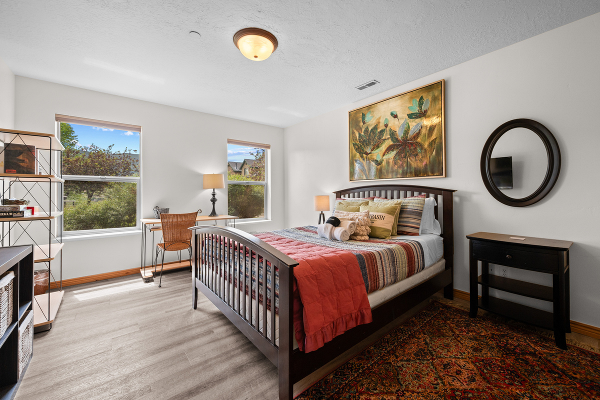 Wake up to mountain views in this inviting bedroom featuring a cozy workspace, stylish decor, and plenty of natural light.