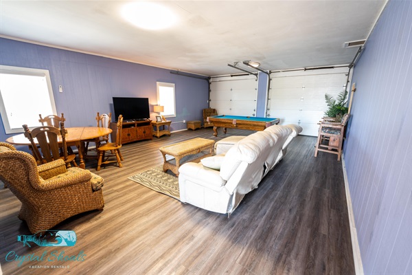 Finished garage on the ground level is air conditioned and offers a smart TV, regulation-sized pool table, card table, and a large leather couch