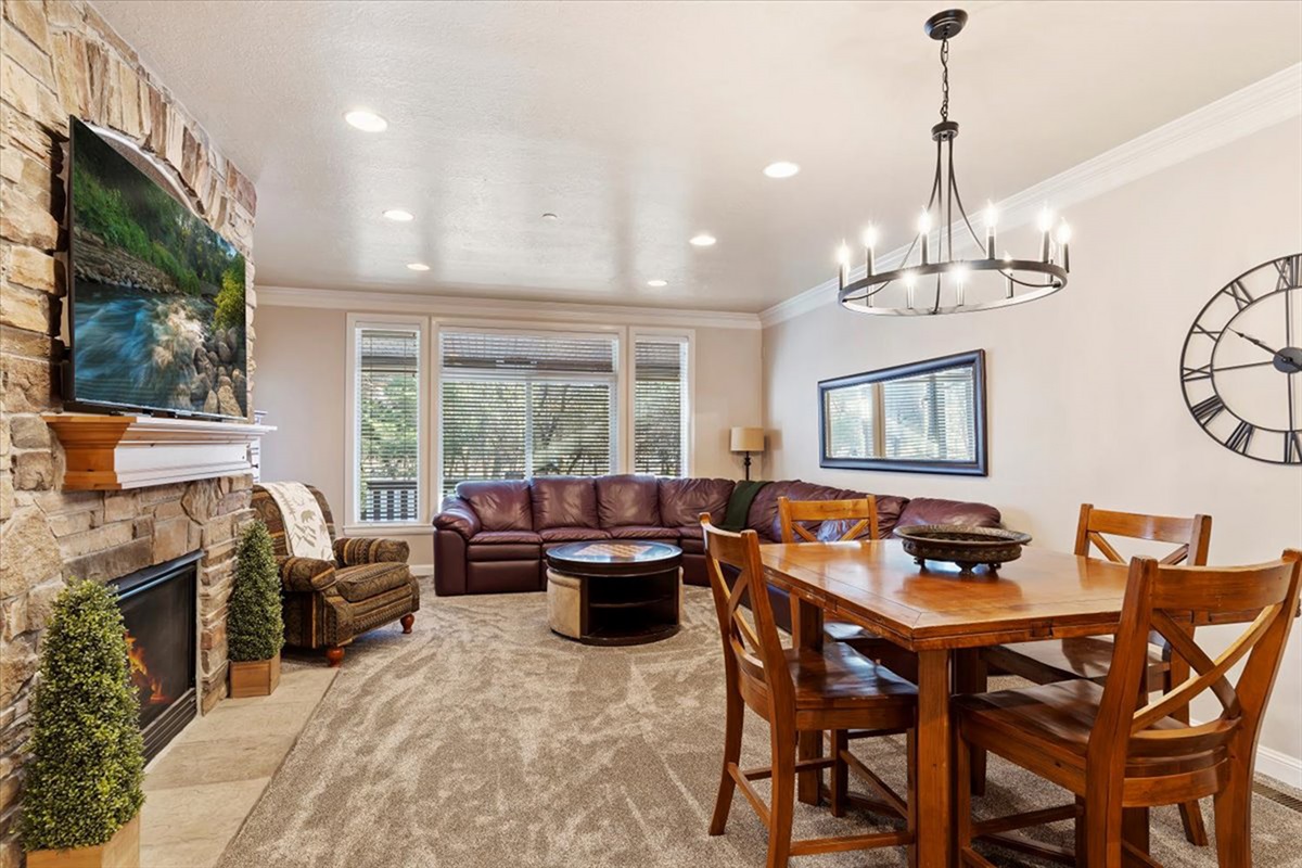 An elegant open-concept living and dining space anchored by a stunning stone fireplace, where warm finishes and refined décor create an inviting atmosphere for gathering.