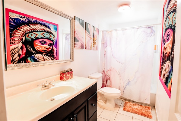 A pristine white bathroom, where cleanliness meets artistry. A beautiful painting reflects in a well-placed mirror, adding a touch of sophistication and depth to the space.