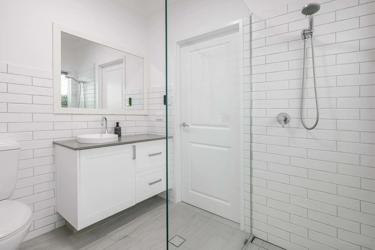 The bathroom includes a walk-in glass shower, rain-style shower head, vanity storage and white subway tiling for a fresh, easy-care space.
