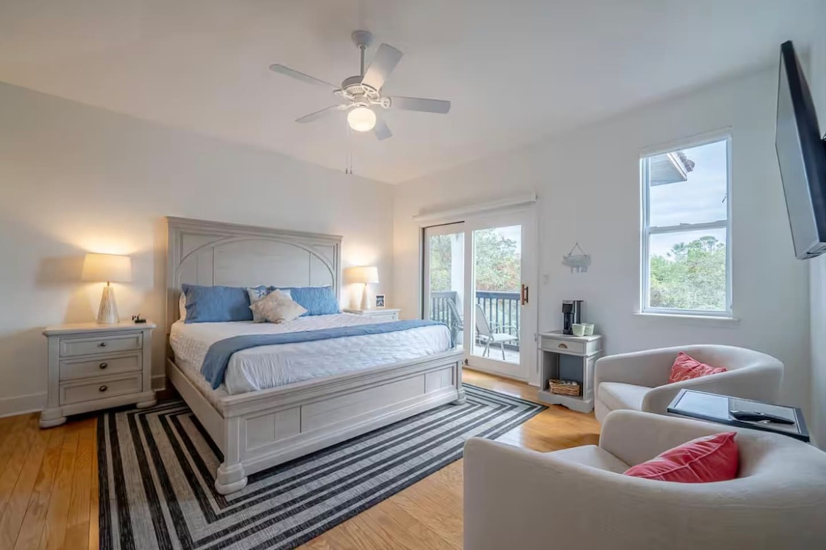 Spacious King bedroom featuring a comfortable king-size bed, cozy armchair seating area, and private balcony access