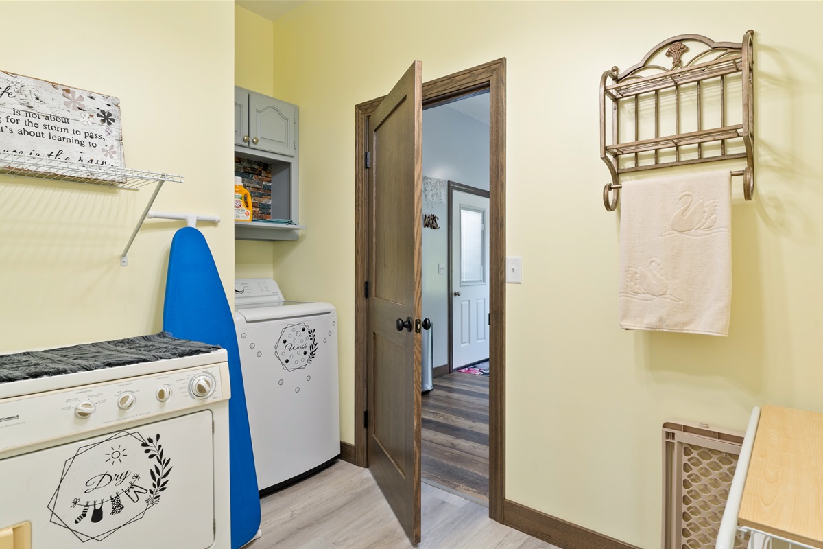 Functional laundry room with washer, dryer, shelving, and rustic accents for added charm.
