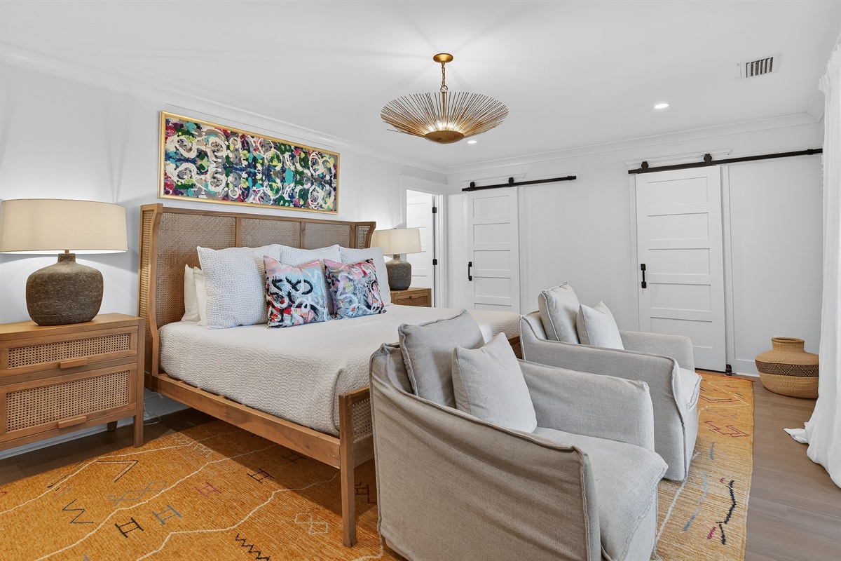 Serene master suite with king bed, curated textures, and cozy seating—your private retreat to unwind and recharge.