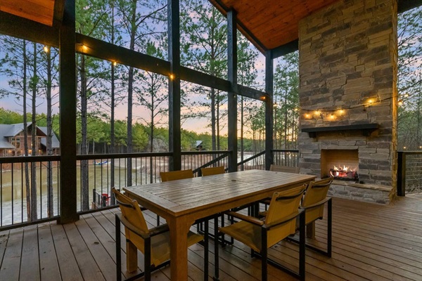 A screened patio with a stone fireplace and rustic dining set offers a lakeview dining experience. This cozy retreat is perfect for enjoying the outdoors in comfort, making it an ideal cabin getaway for those seeking a luxury vacation rental.