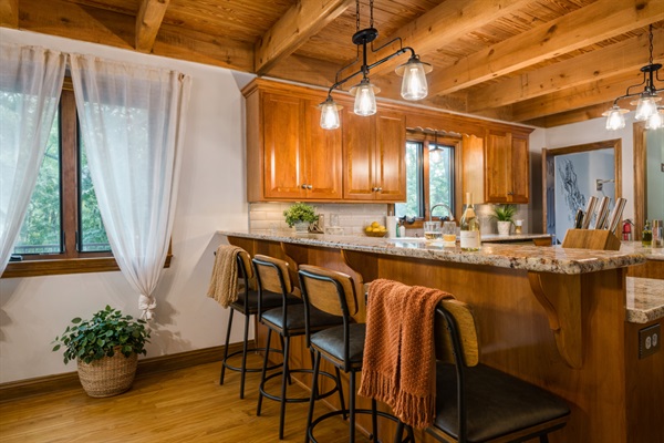 The breakfast bar seats four with a full kitchen view — coffee station on the counter, croissants on the board, morning sorted.