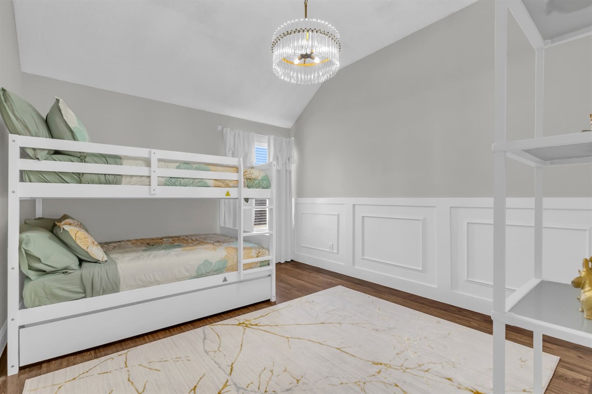 Large bunk room with queen-over-queen beds, blackout blinds, ceiling fan, and modern décor designed for families and shared sleeping arrangements.