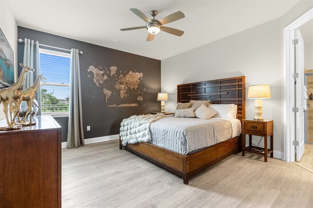 The travel-themed room features a large world map as a focal point on the wall, inspiring adventure. A sleek side table with a modern lamp complements the decor, while a wall-mounted TV adds convenience.