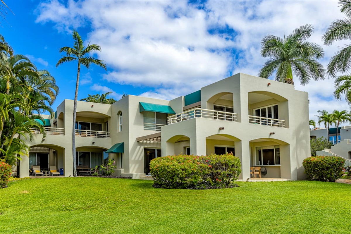 Your ground-floor condo is partially concealed behind the bougainvillea hedge. The turquoise awning center-left is your bedroom window, the wrap-around lanai to the right of the awning. This is a four-plex.
